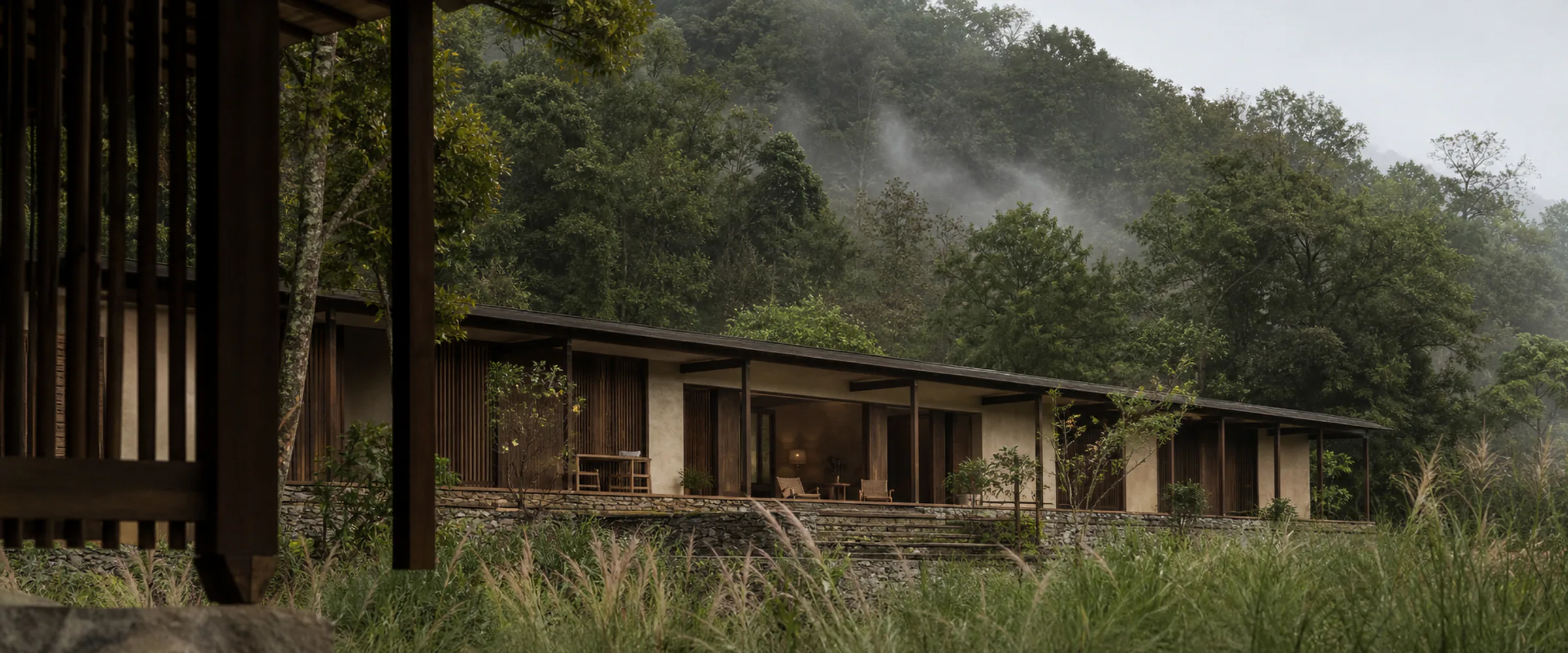 A long view of the house sitting low against the treeline.